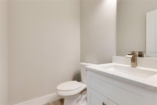 bathroom with toilet, vanity, and wood finished floors