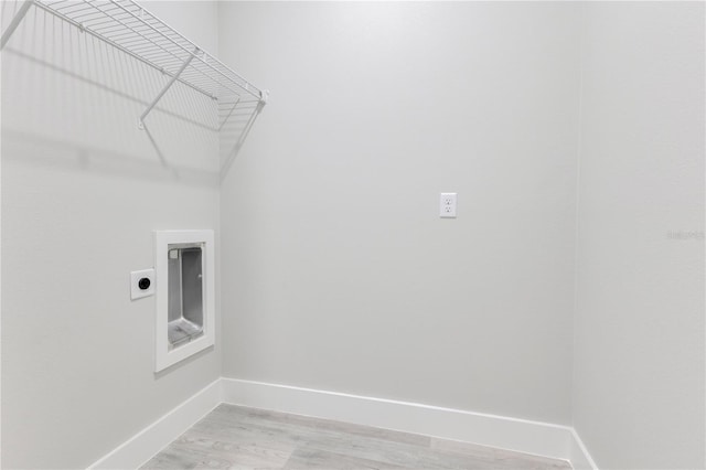 clothes washing area with electric dryer hookup, baseboards, and light wood-type flooring