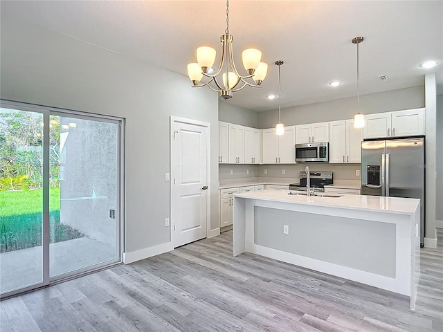 2531 SW 167th Loop, Ocala, FL 34473 - kitchen with stainless steel appliances, light countertops, a sink, light wood-type flooring, and a chandelier