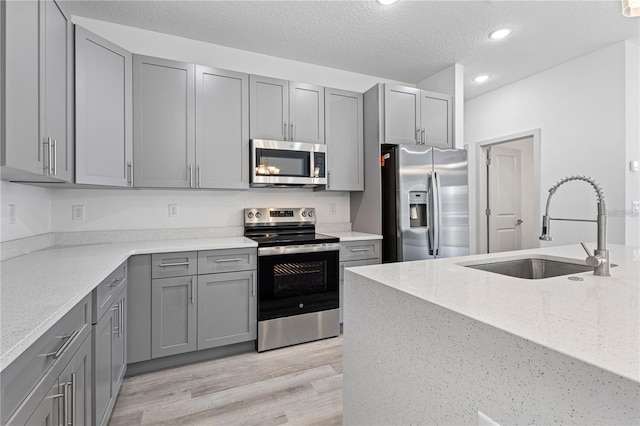 kitchen with stainless steel appliances, gray cabinets, a sink, recessed lighting, and a textured ceiling