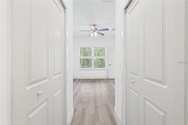 hall with light wood-type flooring and baseboards