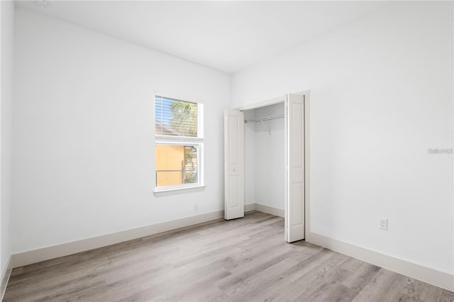 unfurnished bedroom featuring wood finished floors, a closet, and baseboards