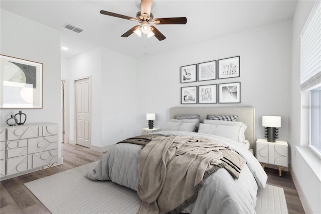 bedroom featuring multiple windows, light wood-style flooring, a ceiling fan, and baseboards