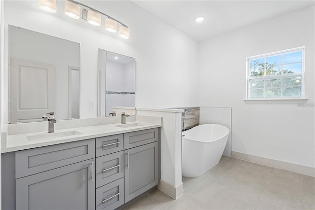 bathroom with baseboards, a freestanding bath, double vanity, and recessed lighting