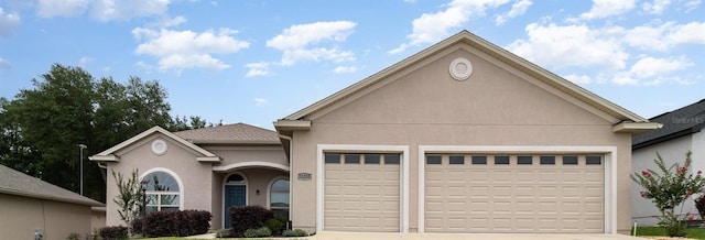 view of front of house with a garage, driveway, and stucco siding