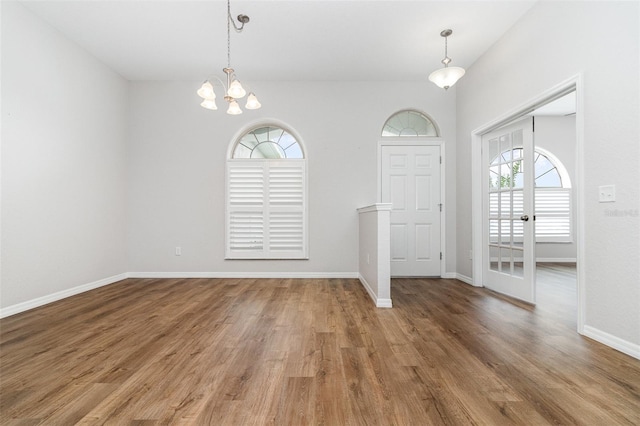 entryway featuring wood finished floors, a chandelier, and baseboards