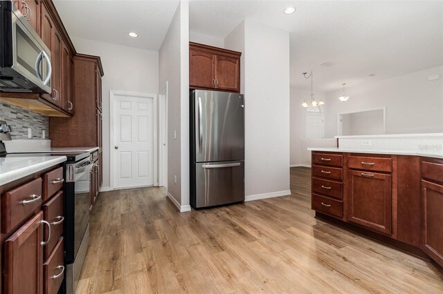 kitchen featuring stainless steel appliances, a chandelier, light countertops, light wood finished floors, and recessed lighting