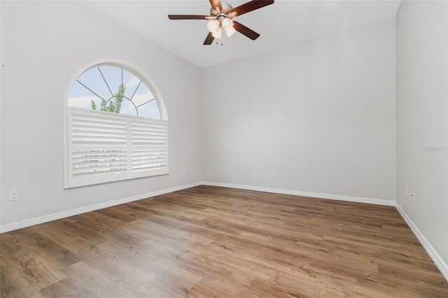 spare room with ceiling fan, light wood-type flooring, lofted ceiling, and baseboards