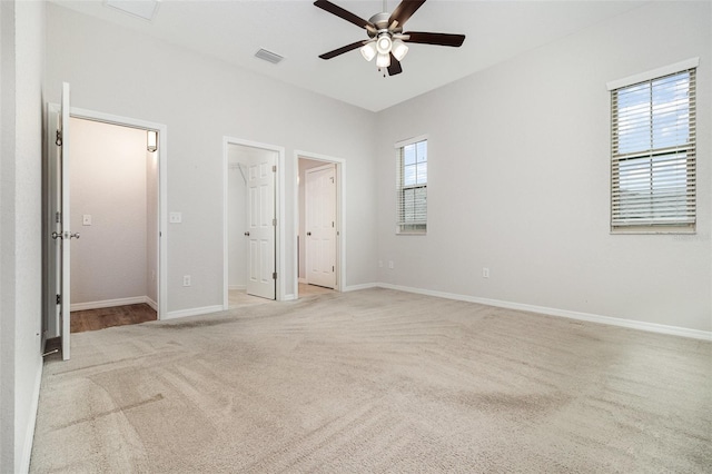 unfurnished bedroom with light colored carpet, a spacious closet, and baseboards