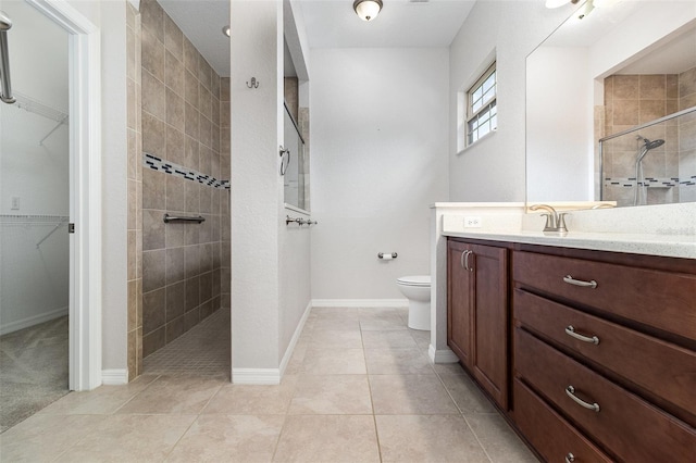 full bath featuring a walk in shower, vanity, a walk in closet, toilet, and tile patterned floors