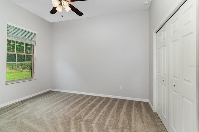 unfurnished bedroom featuring carpet, a closet, baseboards, and ceiling fan