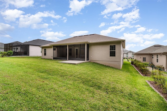 back of house featuring a sunroom, a yard, stucco siding, and a ceiling fan