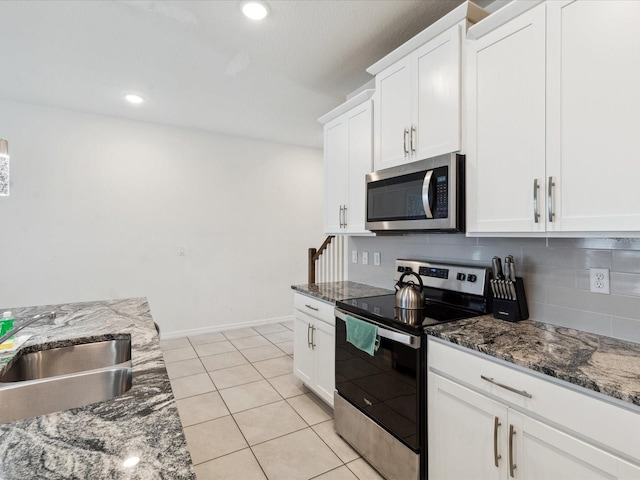 1632 Tropical Palms Cir, Kissimmee, FL 34747 - kitchen with appliances with stainless steel finishes, a sink, white cabinets, backsplash, and dark stone counters