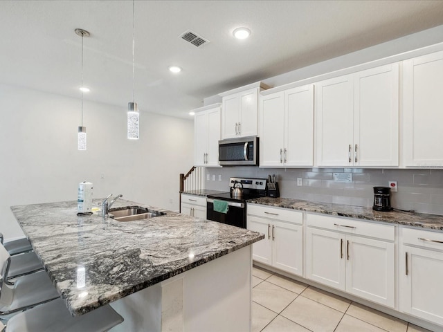 1632 Tropical Palms Cir, Kissimmee, FL 34747 - kitchen featuring electric stove, stainless steel microwave, a sink, white cabinets, and a breakfast bar