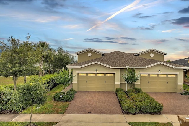 traditional-style home with stucco siding, decorative driveway, and a garage