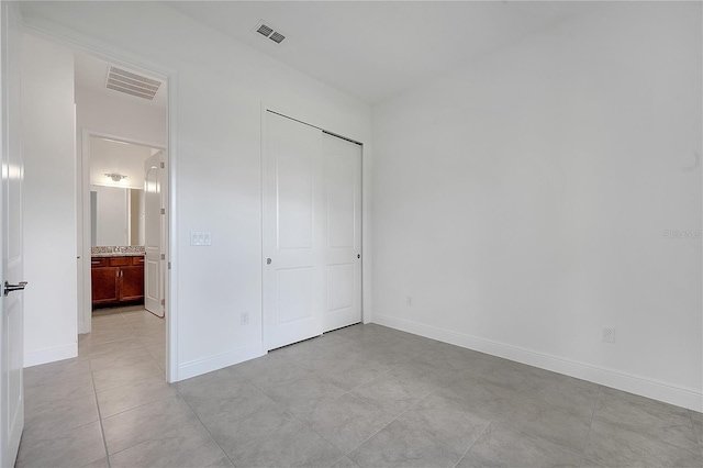 unfurnished bedroom with baseboards, light tile patterned floors, and a closet