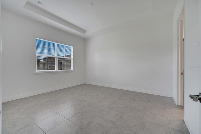 unfurnished room with a raised ceiling, light tile patterned floors, baseboards, and a smoke detector