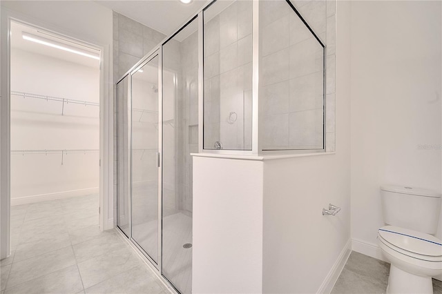 full bath with toilet, a shower stall, baseboards, and a spacious closet