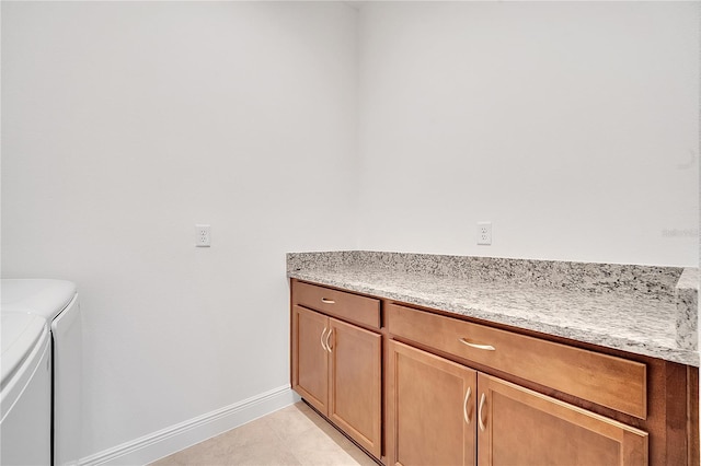 clothes washing area featuring separate washer and dryer, cabinet space, and baseboards