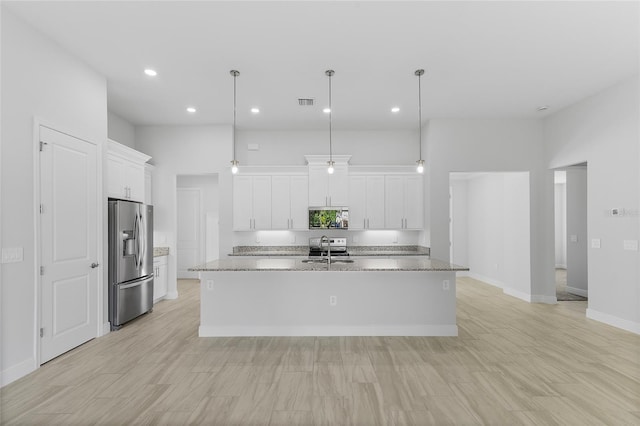 0 Overton St, Orlando, FL 32833 - kitchen featuring appliances with stainless steel finishes, a sink, a center island with sink, white cabinets, and hanging light fixtures