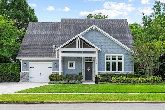 craftsman house featuring an attached garage, a front yard, concrete driveway, and a shingled roof