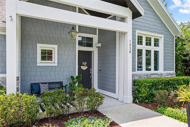 view of exterior entry featuring stone siding and a porch
