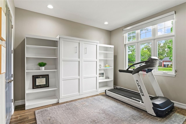 exercise room featuring wood finished floors, baseboards, recessed lighting, and baseboard heating