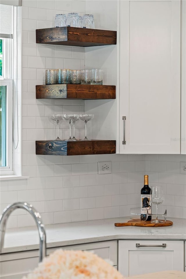 kitchen featuring tasteful backsplash, white cabinetry, light countertops, and open shelves
