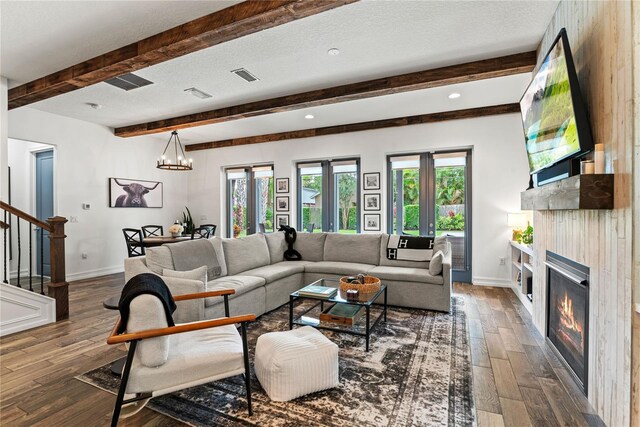 living area with stairway, a glass covered fireplace, wood finished floors, baseboards, and plenty of natural light