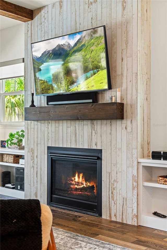 detailed view of a glass covered fireplace, wood finished floors, and wooden walls