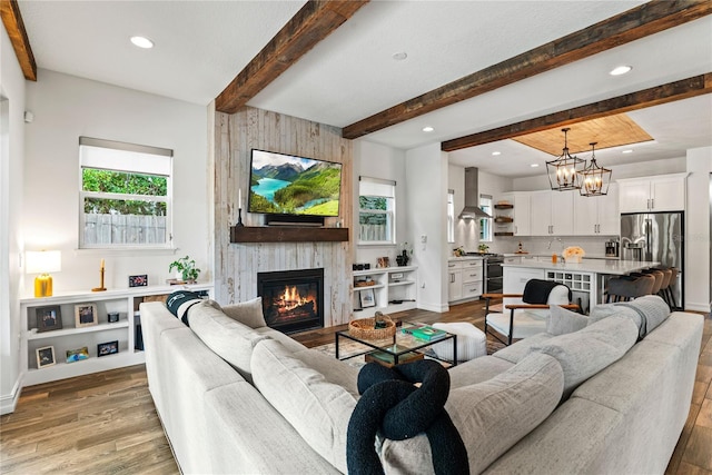 living room with beamed ceiling, light wood-style flooring, a large fireplace, recessed lighting, and baseboards