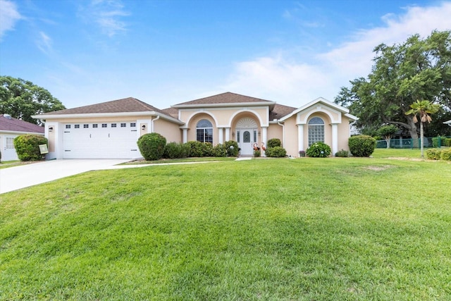 mediterranean / spanish-style house featuring stucco siding, an attached garage, driveway, and a front yard