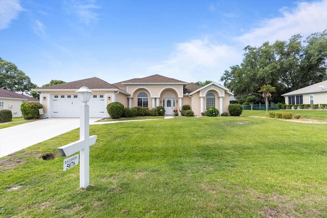 view of front of property featuring an attached garage, driveway, a front lawn, and stucco siding