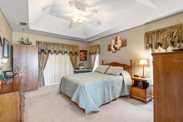carpeted bedroom featuring a raised ceiling and ceiling fan