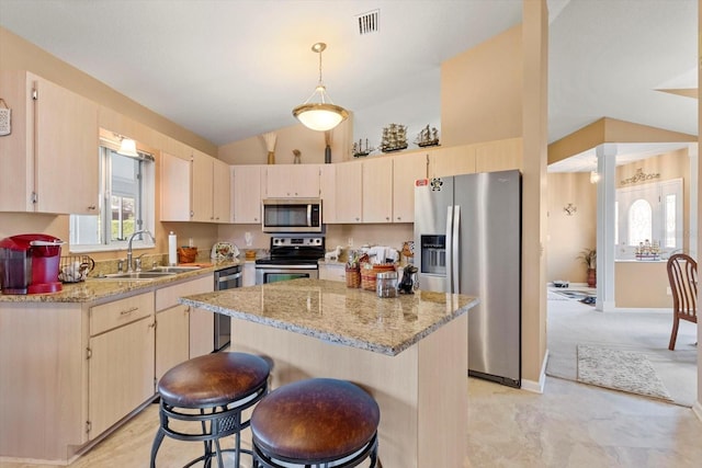 kitchen featuring appliances with stainless steel finishes, lofted ceiling, a sink, plenty of natural light, and a kitchen island