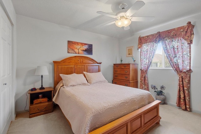 bedroom with light carpet, ceiling fan, and a closet