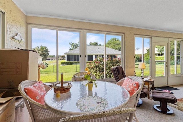 sunroom featuring healthy amount of natural light, ornamental molding, and french doors