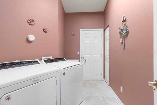 laundry room featuring washing machine and dryer, light marble finish flooring, and baseboards