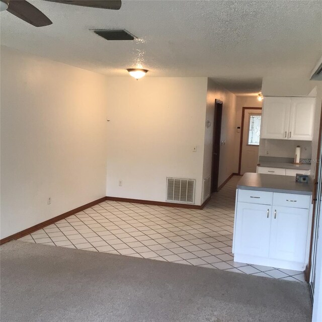 3152 Clewiston St, Deltona, FL 32738 - kitchen featuring white cabinets, light tile patterned floors, light carpet, and a textured ceiling