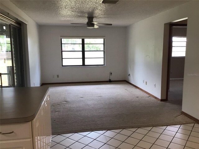 3152 Clewiston St, Deltona, FL 32738 - empty room with light colored carpet, a ceiling fan, a textured ceiling, baseboards, and light tile patterned floors