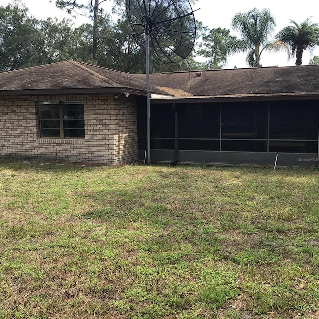 3152 Clewiston St, Deltona, FL 32738 - back of house with a sunroom, a yard, brick siding, and a shingled roof