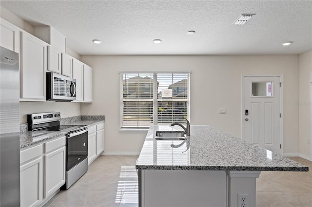 17081 Water Spring Blvd, Winter Garden, FL 34787 - kitchen featuring stainless steel appliances, a sink, a textured ceiling, light tile patterned floors, and a center island with sink