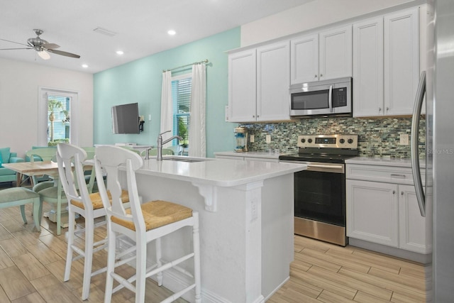 8045 Lost Shaker Ln, Kissimmee, FL 34747 - kitchen with appliances with stainless steel finishes, tasteful backsplash, light countertops, light wood-type flooring, and ceiling fan