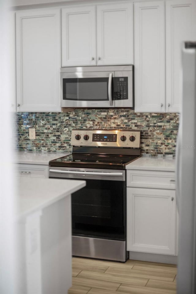 8045 Lost Shaker Ln, Kissimmee, FL 34747 - kitchen with stainless steel appliances, light countertops, backsplash, and white cabinets