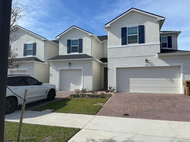 view of front of house with an attached garage, decorative driveway, and stucco siding