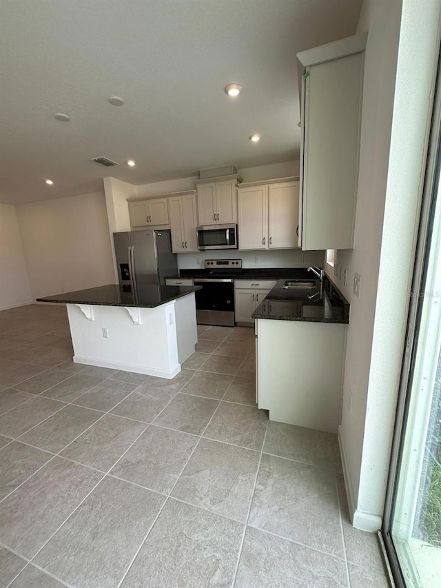 kitchen with stainless steel appliances, light tile patterned floors, dark countertops, a center island, and recessed lighting