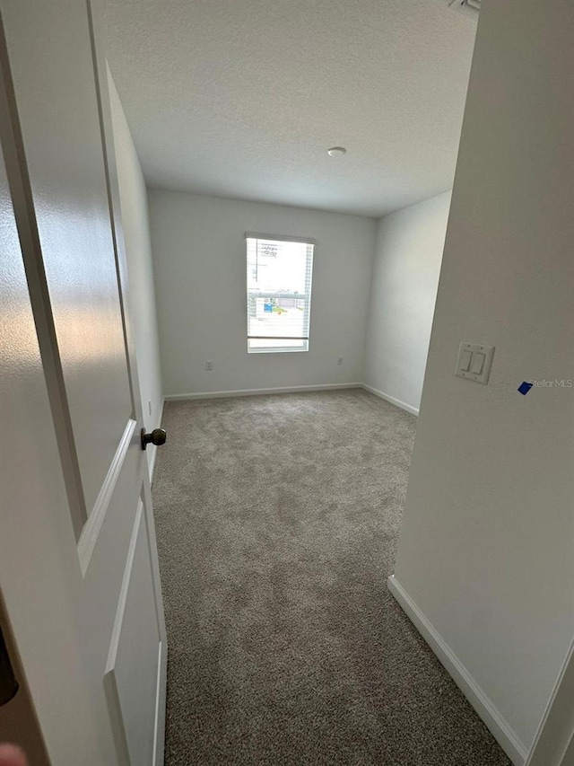 carpeted empty room with baseboards and a textured ceiling