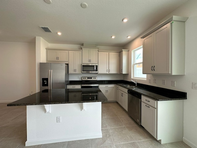 kitchen with appliances with stainless steel finishes, a sink, a center island, a breakfast bar, and recessed lighting