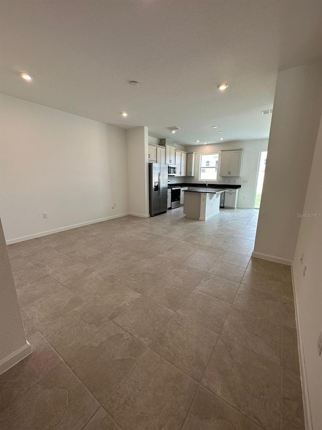 unfurnished living room with recessed lighting and baseboards