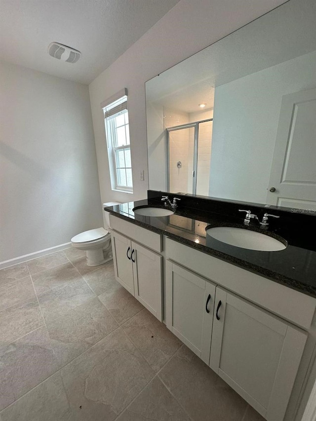 full bath with a stall shower, baseboards, double vanity, and toilet